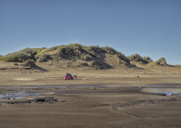 宁静的独处:小帐篷，在沙丘和蓝天的孤独海滩图片下载