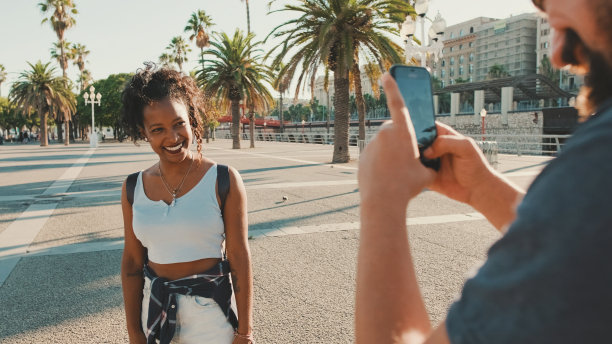 微笑的跨种族情侣。男子用电话给女子拍照并录像图片下载
