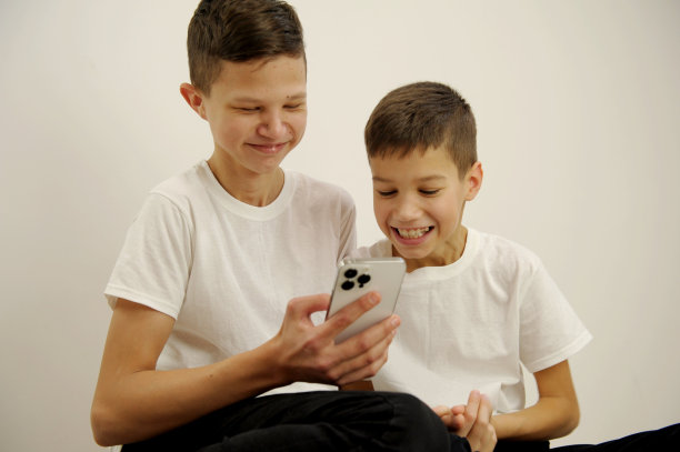 在学校课间休息时，孩子们使用现代智能手机，眼睛睁得大大的，情绪很惊讶。儿童，科学教育理念图片下载