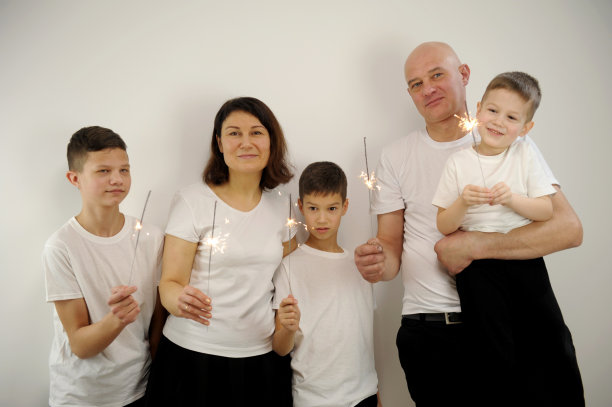 中年夫妇享受时光与三个孩子在白色背景快乐的家庭母亲，父亲和孩子庆祝圣诞节和新年，灯光闪闪图片下载