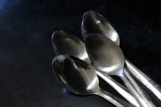 厨房桌子上黑色背景下的一堆勺子图片下载