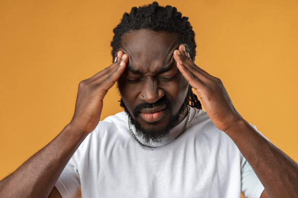 年轻的非洲男子抱着头痛的头在黄色的背景图片下载