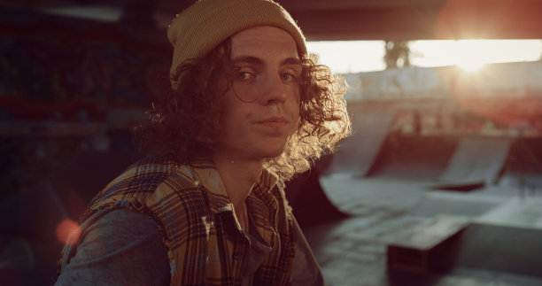 放松的青少年男子休息训练后在滑板公园。镜头前的人。图片下载