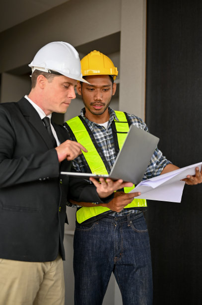 坚定的亚洲男性工头看着笔记本电脑屏幕，和一个白人商人一起工作图片下载