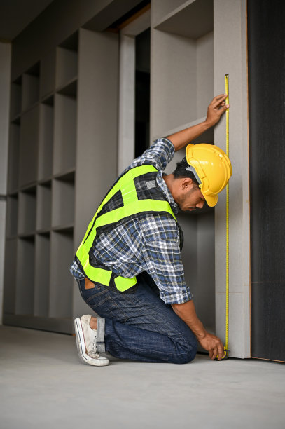专业的亚洲男性建筑检验员用卷尺测量墙壁图片下载