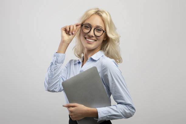 成功的年轻女商人，正装拿着笔记本电脑和触摸眼镜，对着镜头微笑图片下载