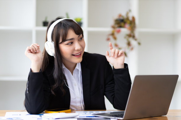 年轻迷人的亚洲商业女性在休息时间听音乐和玩的放松工作。图片下载