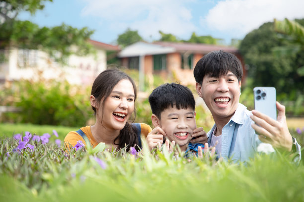 快乐的亚洲家庭坐在户外的花园里，用手机自拍。美丽的记忆。图片下载