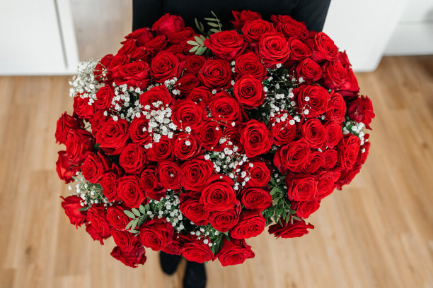 一个女孩手里捧着一大束他们的红玫瑰。周年的祝贺。花园鲜红的玫瑰。花交付图片下载