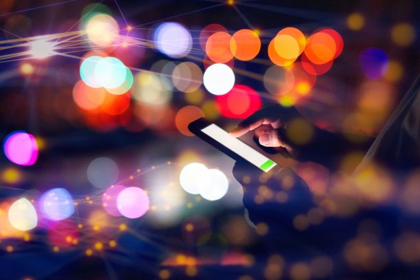 男子在城市灯光的背景下使用智能手机图片下载