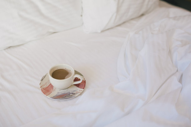 在酒店房间的白色床上喝杯咖啡。图片下载