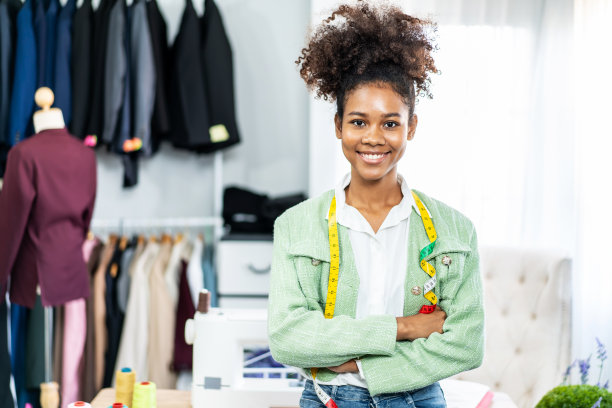 女时装设计师在工作室工作的肖像，裁缝双臂交叉站立，制衣车间的卷尺，女裁缝，在工作室的人体模型上裁剪衣服。图片下载