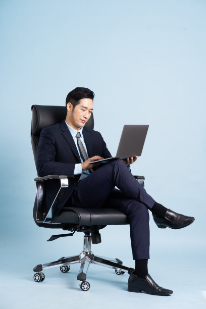 亚洲商人男性肖像坐在椅子上，孤立在蓝色背景上图片下载