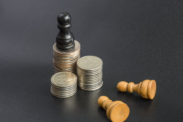 金钱的权力概念。黑木棋卒站在钱币上，两个白棋卒倒在地上，鞠躬图片下载