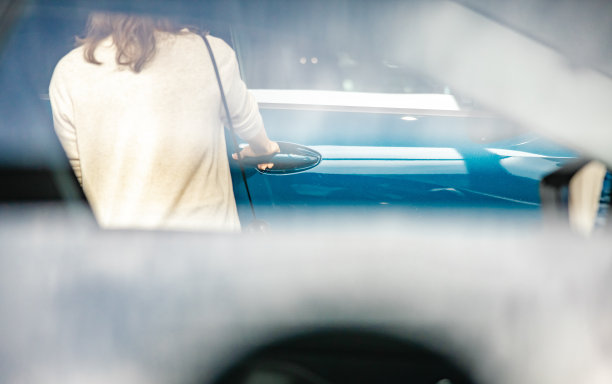 一名女子正在一家汽车经销商的室内打开一辆新SUV的车门，前面是家庭用车，注意看背景图片下载