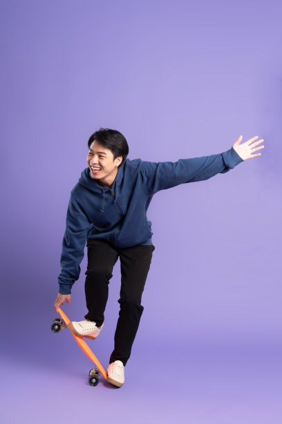 年轻的亚洲男子在紫色背景上玩滑板的图像图片下载