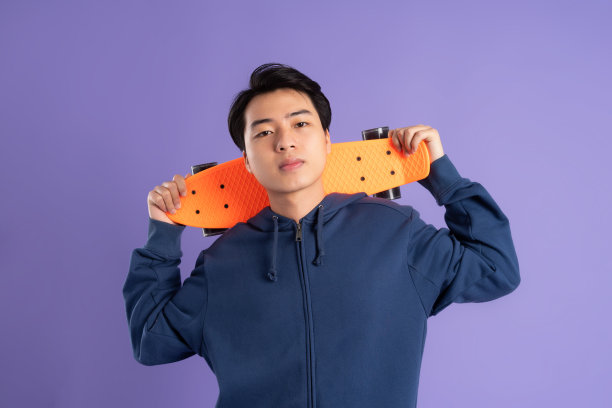 年轻的亚洲男子在紫色背景上玩滑板的图像图片下载