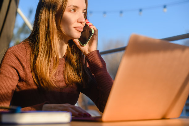 一名女子坐在酒店的桌子上打电话。图片下载