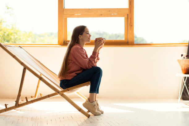 十几岁的女孩喝热可可，休息在舒适的扶手椅在家里，侧视图，自由的空间图片下载
