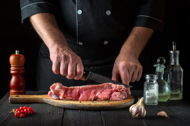 厨师在烤之前用刀切肉。餐厅餐桌上为准备美味午餐准备的香料。图片下载