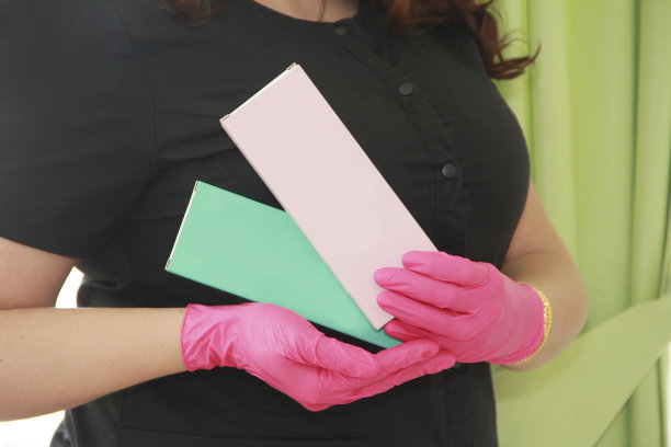 一位戴着粉色手套的美容医生的手拿着一个装有药物制剂的盒子图片下载