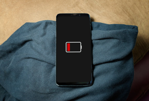 屏幕上低电量图标的智能手机特写。在表格背景上图片下载