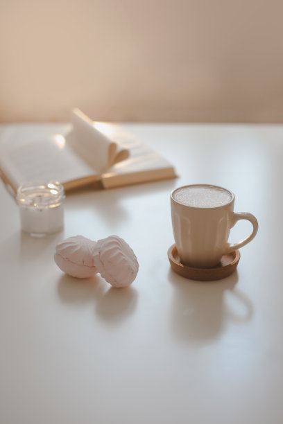 咖啡杯，花，蜡烛和一本书在白色的桌面背景俯视图。简约的家庭室内装饰图片下载