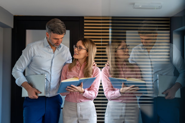 企业专业人士，男女经理在现代化的办公走廊里散步交谈图片下载