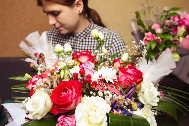 散焦美女与鲜花的礼物阅读随附卡片。画像的年轻女性花店与许多玫瑰束和花束。花店。焦点不清图片下载