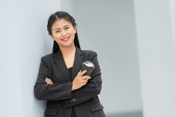 亚洲女商人站着的肖像，她穿着黑色西装，微笑着站在一个好心情。有一个复制空间和隔离。图片下载