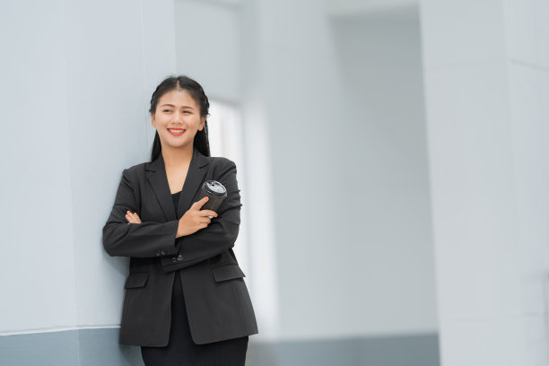 亚洲女商人站着的肖像，她穿着黑色西装，微笑着站在一个好心情。有一个复制空间和隔离。图片下载