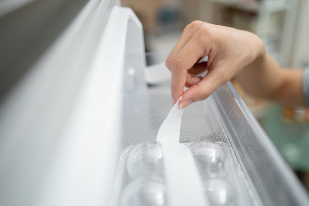 裁剪妇女的手拆除一个新冰箱的保护贴纸图片下载