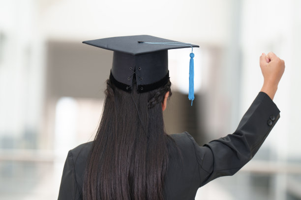 一个年轻的亚洲女子大学毕业生毕业礼服和帽子的后视图图片下载