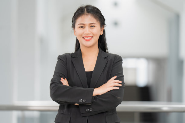 亚洲女商人站着的肖像，她穿着黑色西装，微笑着站在一个好心情。有一个复制空间和隔离。图片下载