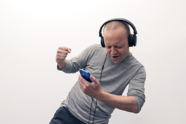 年轻人戴着耳机，手里拿着手机，喜欢听音乐图片下载