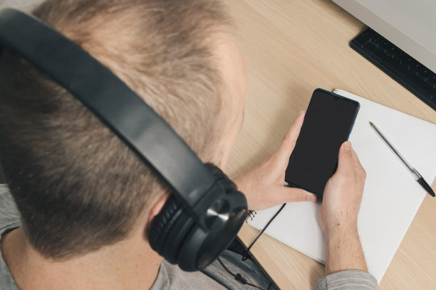 年轻人戴着耳机，手里拿着手机图片下载