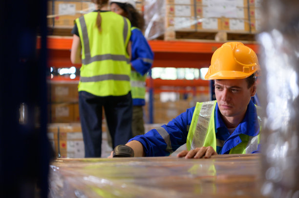 汽车零部件仓库里的一群员工正在检查准备运往汽车装配厂的汽车零部件。图片下载