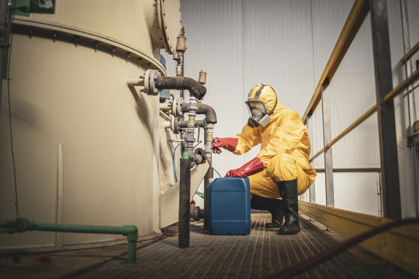 为金属工厂镀锌提供酸和化学品。工人们穿着黄色防护服，戴着防毒面具，手里拿着装有攻击性物质的塑料罐。图片下载