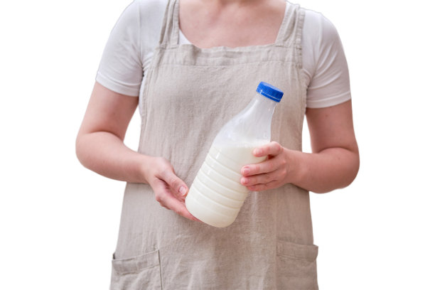 厨房里一个女人手里拿着一瓶牛奶，孤零零地放在白色背景上。女性的手拿着装有牛奶的塑料瓶图片下载