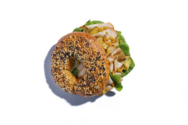 小圆面包配芝麻，沙拉，猪肉，芥末，腌黄瓜和酱汁，放在白盘子里图片下载