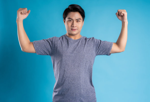 亚洲年轻男子在蓝色背景上摆姿势图片下载