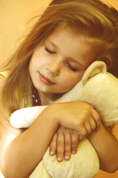 小女孩在家里抱着她的玩具熊。小女孩和她的玩具朋友分享秘密。图片下载