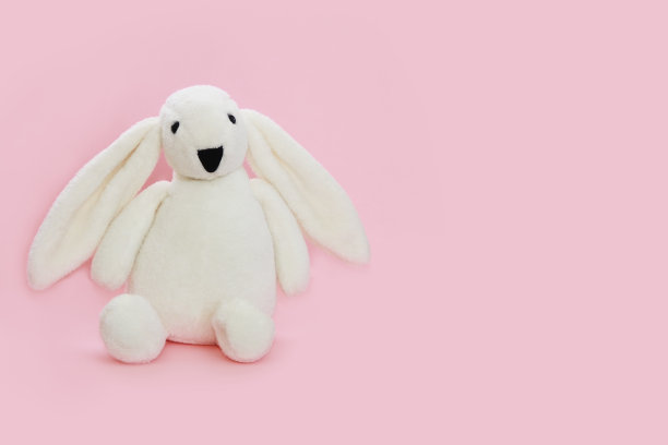 儿童的软玩具白色毛绒兔子坐在粉红色的背景图片下载