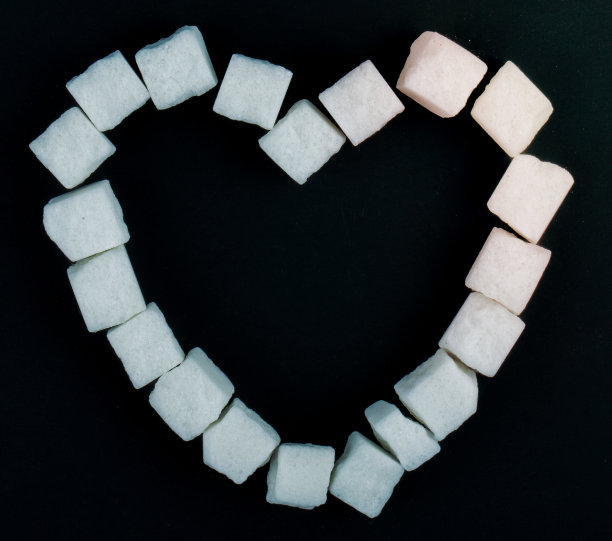 俯视图的方糖排列在一个形状的心形黑色背景图片下载