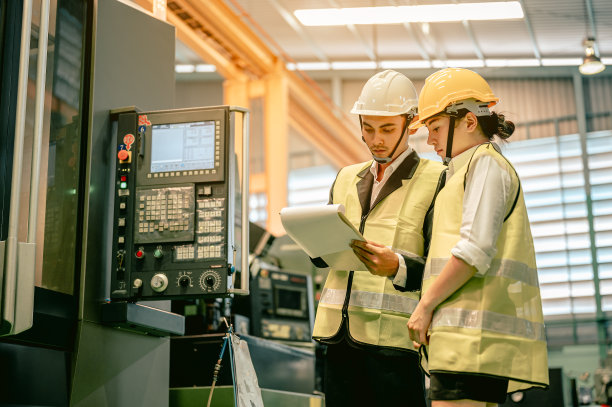 一男一女工程师正在检查一台工业机器的控制面板。工程师和建筑师的概念。图片下载