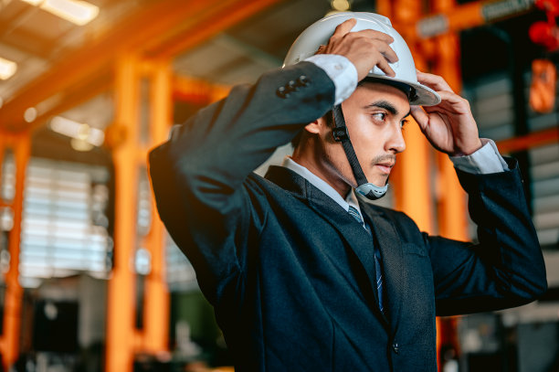男工程师经理在检查工厂内的机器之前戴着安全帽。工程师和建筑师的概念。图片下载