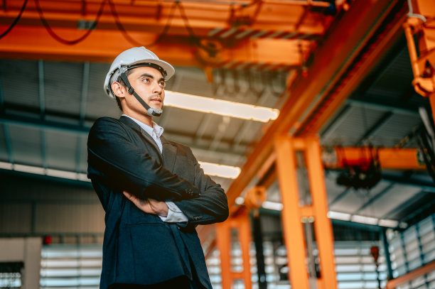 年轻的亚洲军人在机器室内工厂快乐地微笑。工程师和建筑师的概念。图片下载