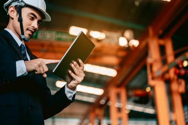 工程师经理检查平板上的手册，并命令工人使用车床、机器、机械手进行铣削设备。工程师和建筑师的概念。图片下载