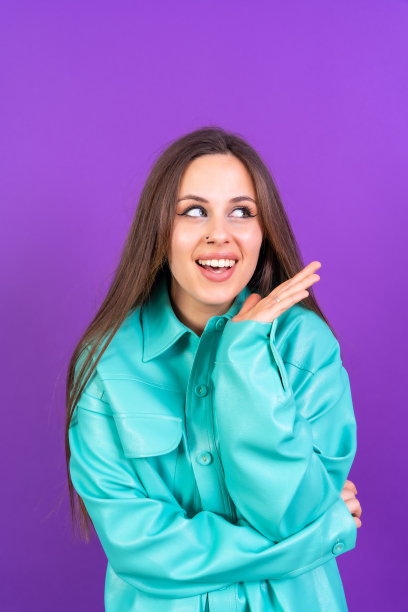 近距离的肖像年轻女子，开朗孤立在紫色工作室背景在蓝色风衣，垂直照片图片下载