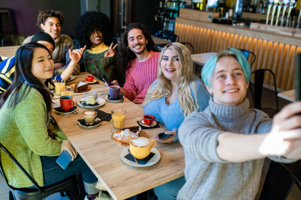 年轻的朋友们在酒吧面包房敬酒喝早餐，快乐的潮人喝卡布奇诺吃蛋糕，友谊概念，关注金发女郎图片下载